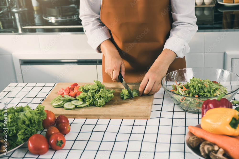 Asian woman uses a knife to cut the salad greens in the kitchen. Asian woman uses a knife to cut the salad greens in the kitchen.