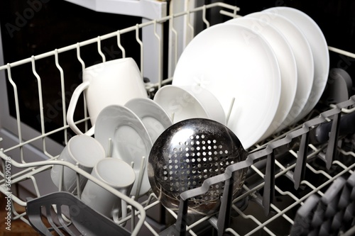 Dishwasher with clean white dishes in the kitchen