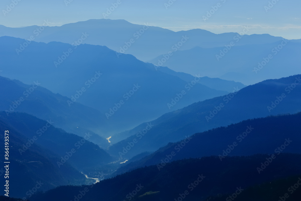 Silhouette of mountain ranges with a river flowing through them during an early morning at Sikkim India