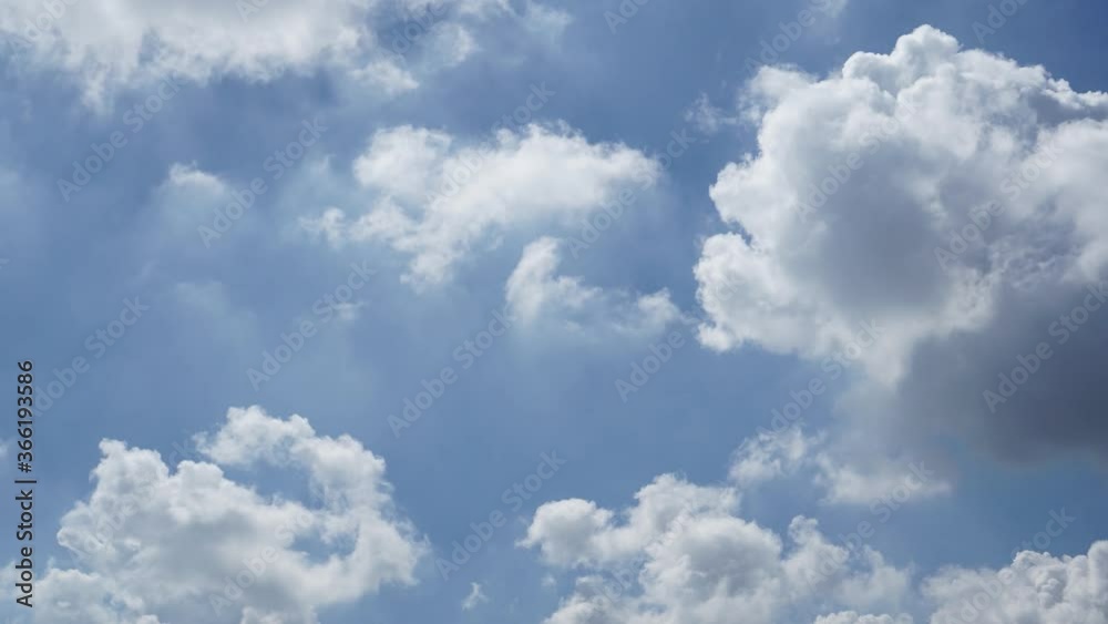 Time lapse of white fluffy clouds over blue sky.
