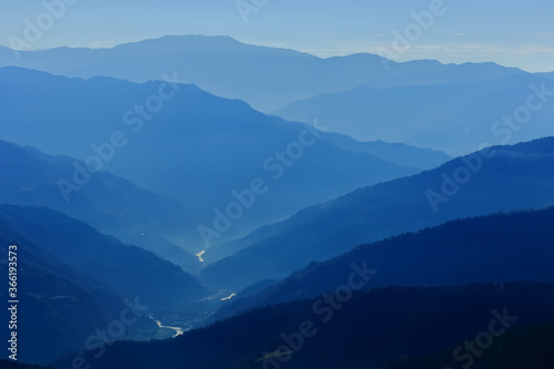 Fototapeta Naklejka Na Ścianę i Meble -  Silhouette of mountain ranges with a river flowing through them during an early morning at Sikkim India