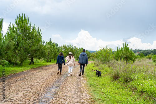 Un hombre y dos jóvenes están caminando con su perro por el bosque.