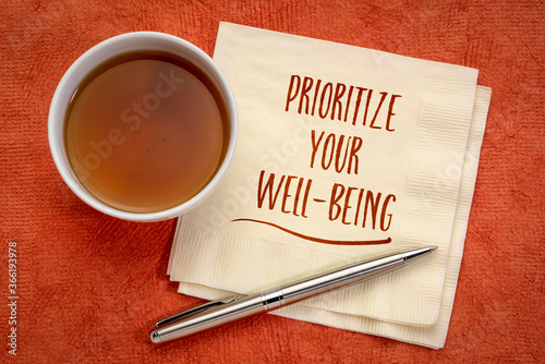 prioritize your well-being inspirational note - handwriting on a napkin with a cup of tea, healthcare, healthy lifestyle and personal development concept photo