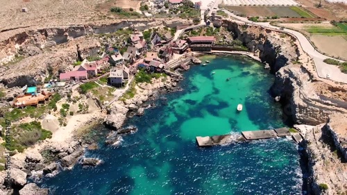 Beautiful small fishing village aerial birds eye shot fly backward bay reveal. Popeye village filming location, Malta. photo