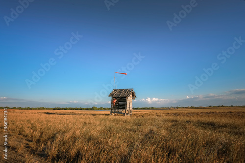 Small red wooden hut on savanna grass during sunset