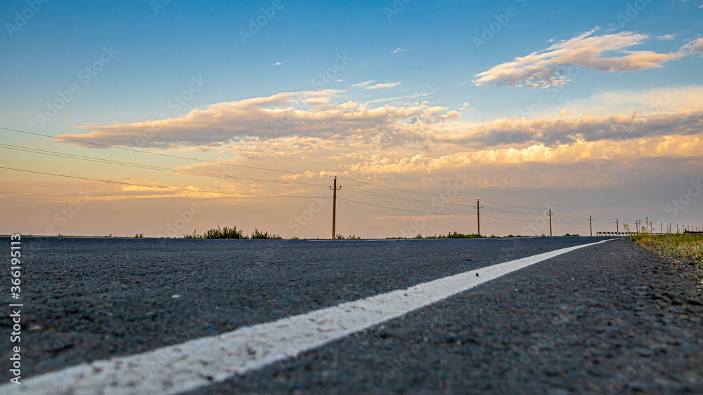 The asphalt road goes into the sunset. Sky and clouds