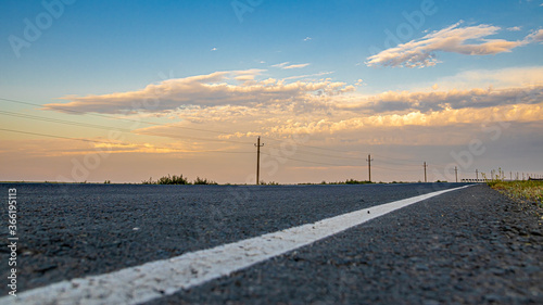 The asphalt road goes into the sunset. Sky and clouds