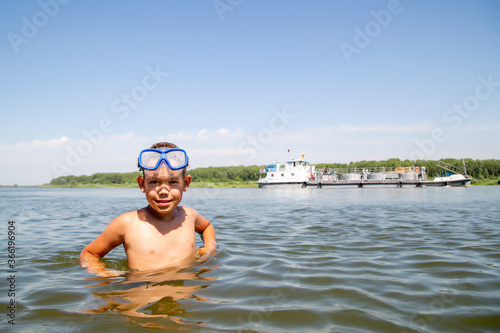 portrait of a little diver against the backdrop of a floating ship