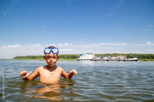 portrait of a little diver against the backdrop of a floating ship