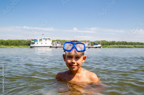 portrait of a little diver against the backdrop of a floating ship