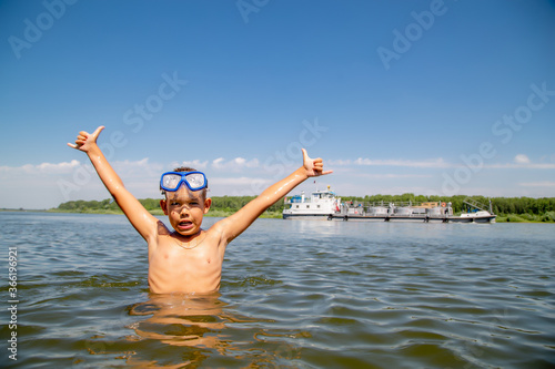 portrait of a little diver against the backdrop of a floating ship