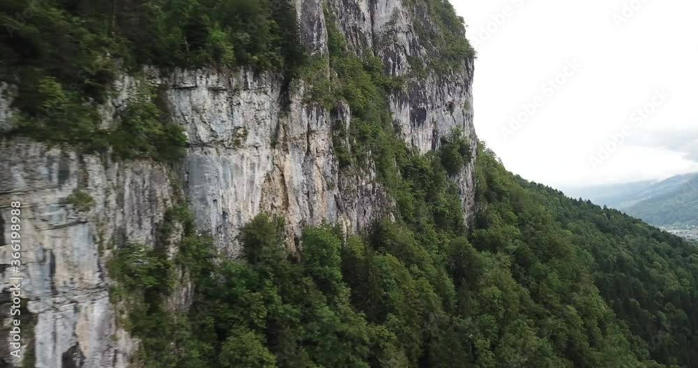 Rocky Cliff With The Lush Green Forest By The Mountains In Obersee In Nafels, Switzerland. - aerial drone Rocky Cliff With The Lush Green Forest By The Mountains In Obersee In Nafels, Switzerland. - aerial drone