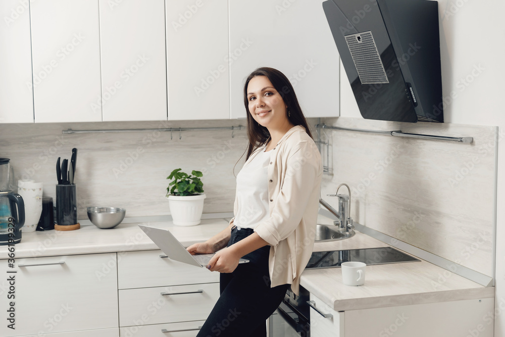 Young woman freelancer working online behind laptop in kitchen home. isolation worker concept Young woman freelancer working online behind laptop in kitchen home. isolation worker concept