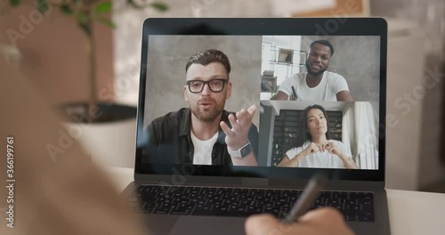 Communication of happy multiracial young people during social distancing. College students listening online lesson and writing notes in notebook. Business chat conference talking with tutor. Close up