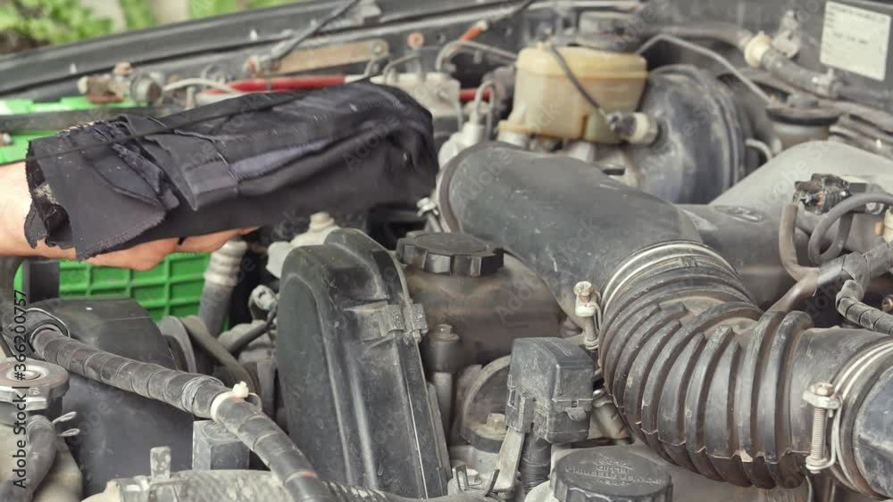 Cars mechanic is checking the level of engine oil from the engine oil level gauge of the car, Automotive industry and garage concepts. Cars mechanic is checking the level of engine oil from the engine oil level gauge of the car, Automotive industry and garage concepts.