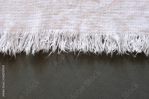 Φωτογραφία Worn fringe trim edges of a white towel against dark surface.