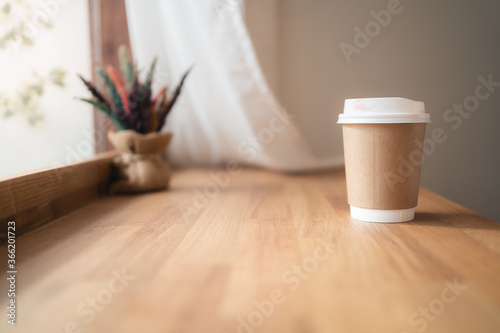 Take away coffee cup with lipstick mark on wooden table in coffee cafe