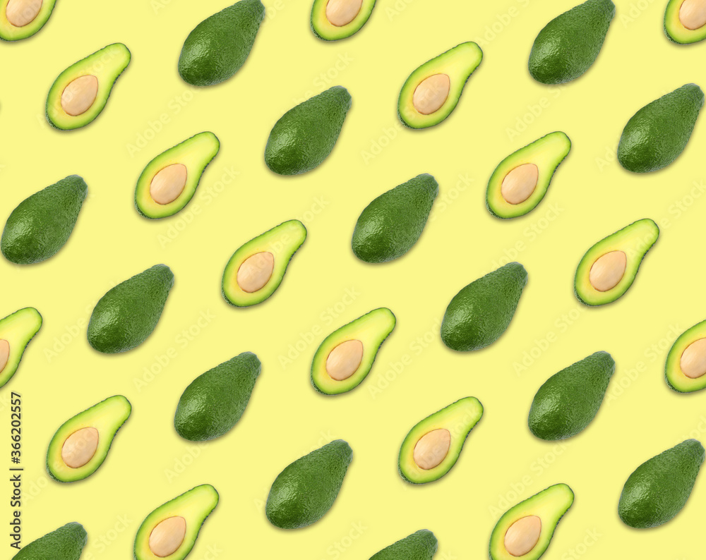 Naklejka premium Pattern of whole and halved avocados on pale yellow background