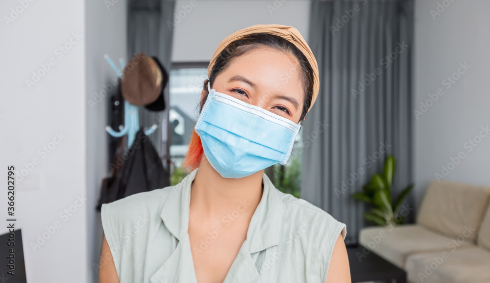 Asian woman smiling behind the mask have a happy face In her house for social distancing concept. Asian woman smiling behind the mask have a happy face In her house for social distancing concept.