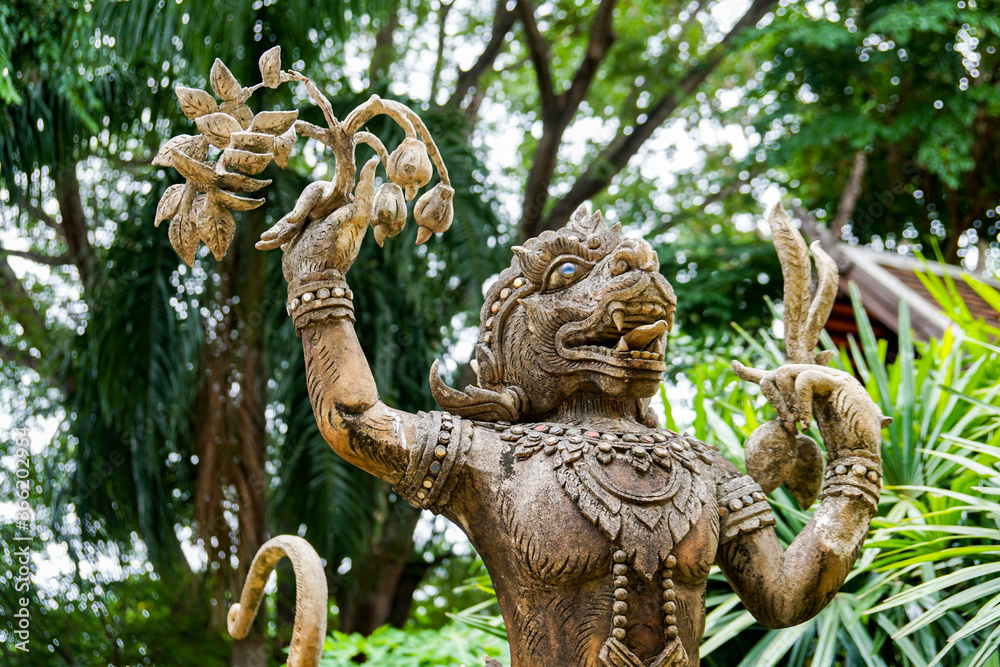 stone statue of a Thai deity, a totem at the entrance to the temple, against a background of greenery
stone statue of a Thai deity, a totem at the entrance to the temple, against a background of greenery