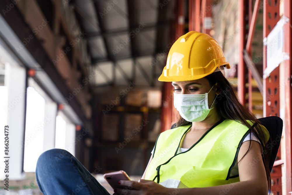 Young engineer worker wears mask and vest working in warehouse factory