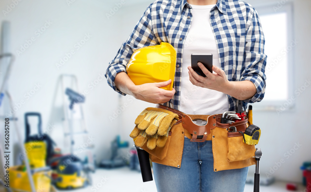 repair, construction and building concept - close up of woman or builder with smartphone, helmet and working tools on belt over utility room background repair, construction and building concept - close up of woman or builder with smartphone, helmet and working tools on belt over utility room background