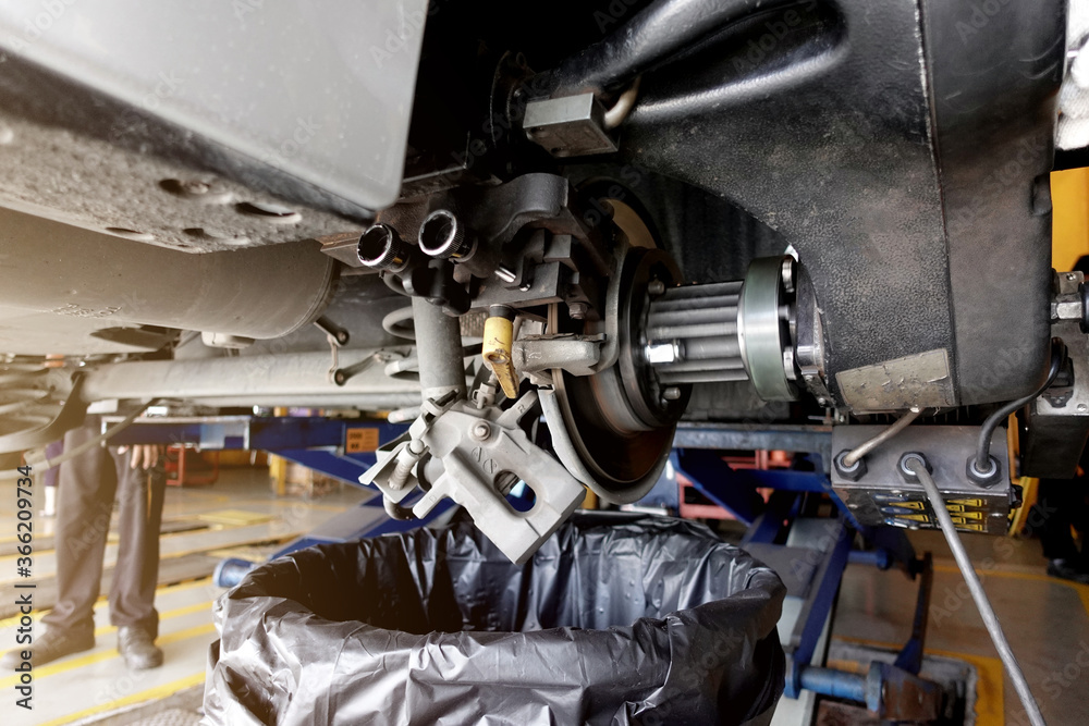 A mechanic repairing, grinding the brake disc and replacing worn out brake pads at an auto repair shop service station - vehicle safety concept A mechanic repairing, grinding the brake disc and replacing worn out brake pads at an auto repair shop service station - vehicle safety concept