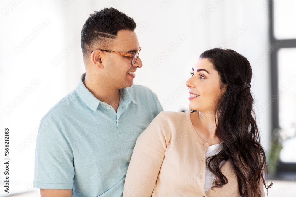 love, relationships and people concept - happy couple looking at each other at home