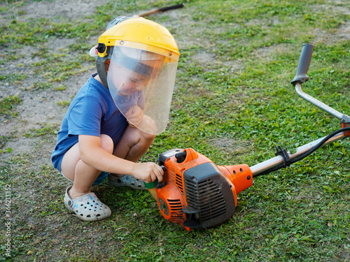 little child wearing a protective mask with a lawn mower