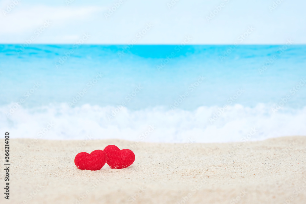 Two red hearts on white sand beach with blurred blue sea Two red hearts on white sand beach with blurred blue sea