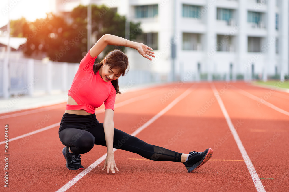 Fototapeta premium Portrait of a young woman runner warm up and stretching before workout in the morning in city stadium. Healthy and recreation stock photo.