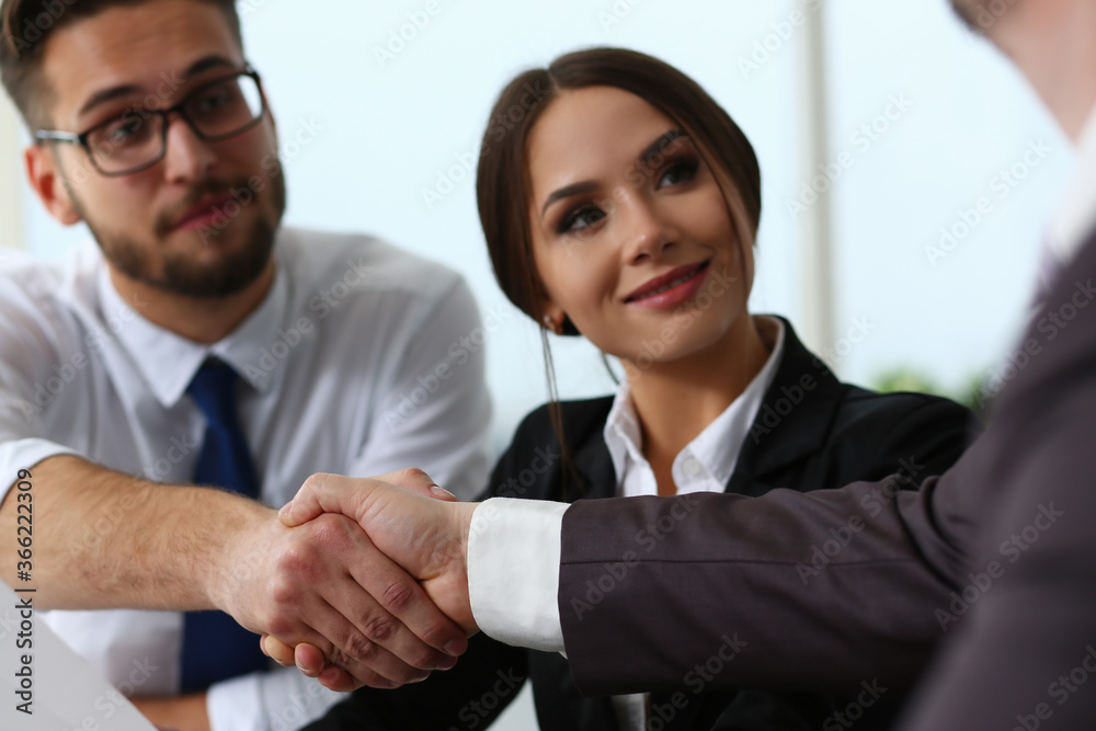 Cheerful male in glasses and female managers are welcoming man visitor and greeting him with hand gesture Cheerful male in glasses and female managers are welcoming man visitor and greeting him with hand gesture