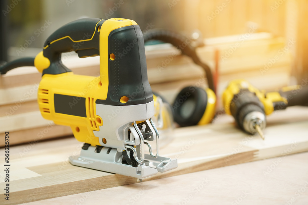 Electric Jigsaw on Walnut Plywood in workshop, jigsaw tool for bevel cuts in wood boards and other materials.woodworking Handicraft and diy concept .selective focus Electric Jigsaw on Walnut Plywood in workshop, jigsaw tool for bevel cuts in wood boards and other materials.woodworking Handicraft and diy concept .selective focus
