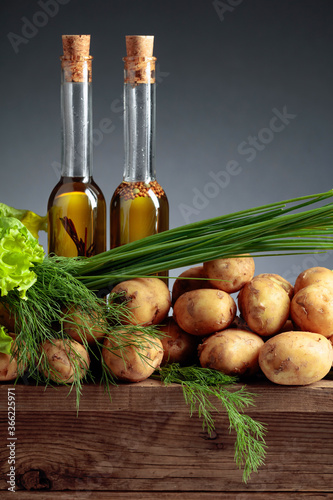 Fototapeta Naklejka Na Ścianę i Meble -  Young fresh organic potatoes with vegetable oil, dill, salad and onion on a wooden table.