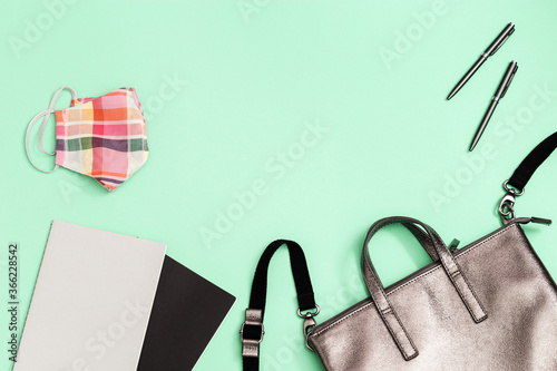 Grey leather backpack with school supplies, face mask, copybooks, pens on paper background with copy space. Back to school concept. Close up, copy space, flat lay.