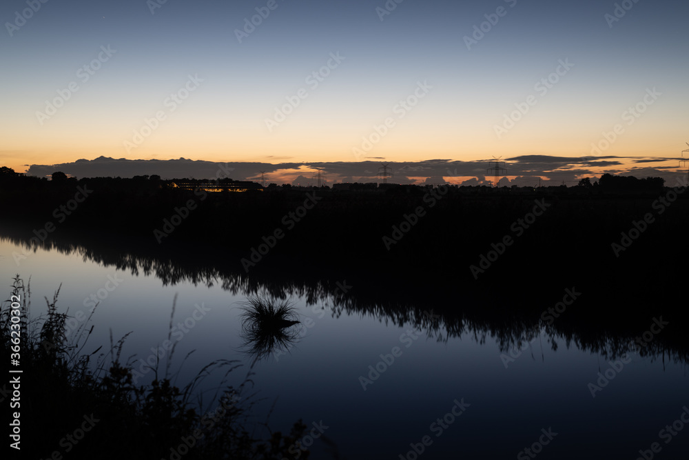 a river glows at night with the horizon along with dark landscape