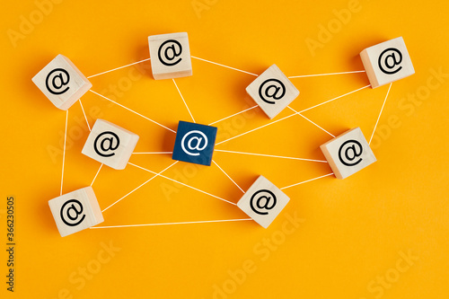 Email at symbol on wooden cubes linked each other with lines. Email traffic or chain mail concept