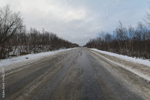 The dirt road is covered with ice .The sky is covered with clouds. © Moroshka