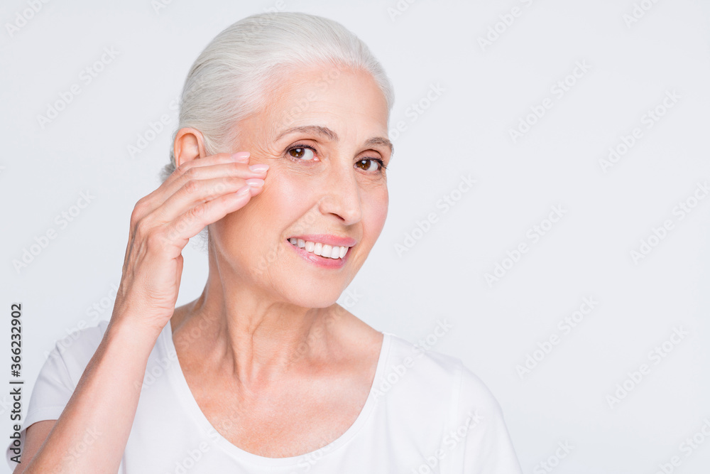 Close-up portrait of nice attractive cheerful cheery content experienced gray-haired lady smoothing perfect clean clear flawless soft skin effective complex isolated over light white grey background Close-up portrait of nice attractive cheerful cheery content experienced gray-haired lady smoothing perfect clean clear flawless soft skin effective complex isolated over light white grey background