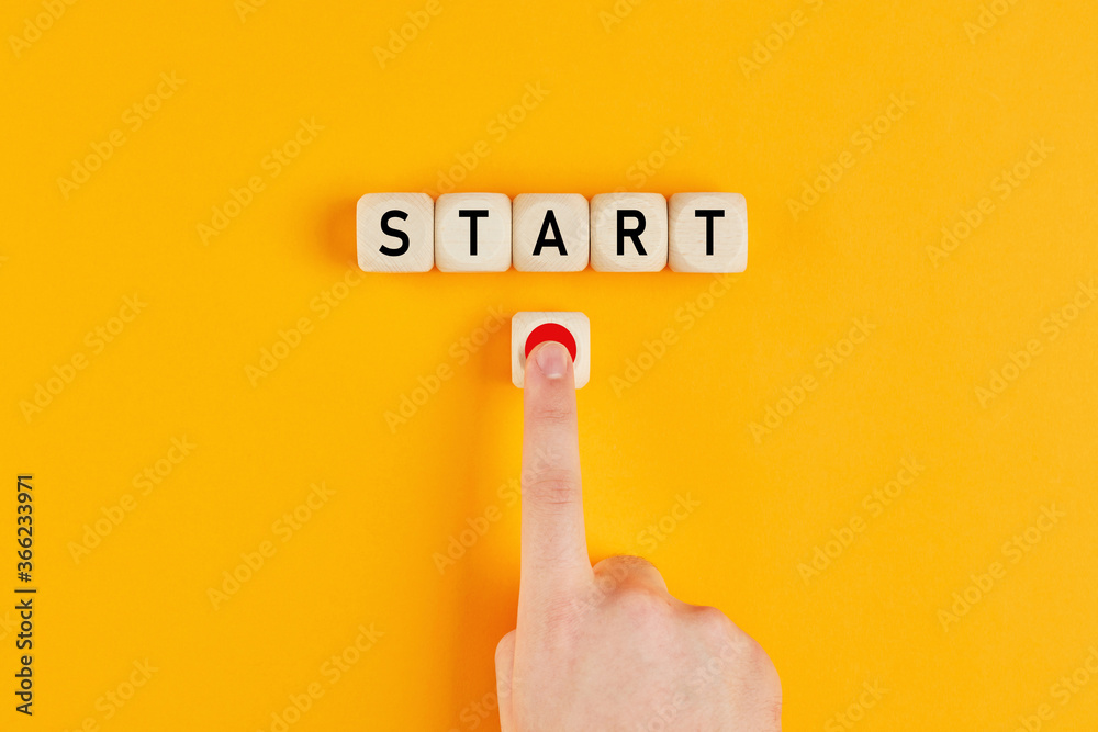The word start on wooden cubes with a male hand pressing the start button. To make a new start in life, business, education or career concept. - obrazy, fototapety, plakaty 