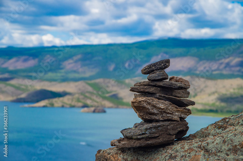 Zen concept. A pyramid made of stone on top of a mountain against the backdrop of Lake Baikal. Stone pyramid for meditation. Harmony and Meditation. Zen stones.