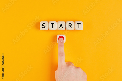 The word start on wooden cubes with a male hand pressing the start button. To make a new start in life, business, education or career concept. photo