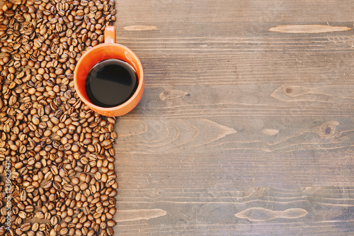 A top view of a cup of coffee with roasted coffee beans on the table