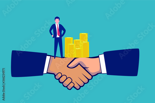 Business financial agreement: businessman standing on big hands shaking each other near stack of coins