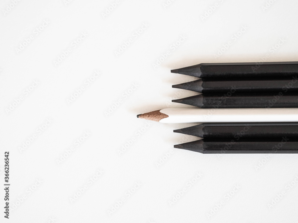 White pencil standing out same crowd black bold pencils on white background, with space text. Leadership, unique, concept.