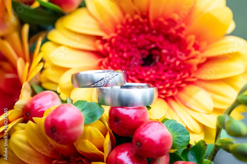 Fototapeta Naklejka Na Ścianę i Meble -  Silver Wedding Ring on yellow and red flowers as symbol of love and human relationships commitment
