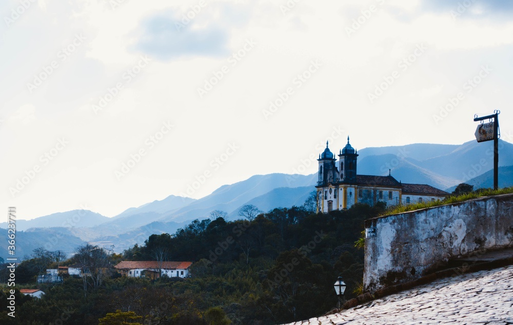 Nossa Senhora das Mercês e Perdões Church located in Ouro Preto, Minas Gerais, viewed from a distance in a cloudy afternoon with hills in the background
