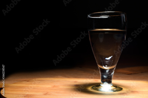 wine glass with wine on wooden table with black background.