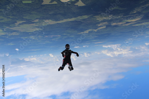 Skydiving. A young woman is flying in the sky in head down position.