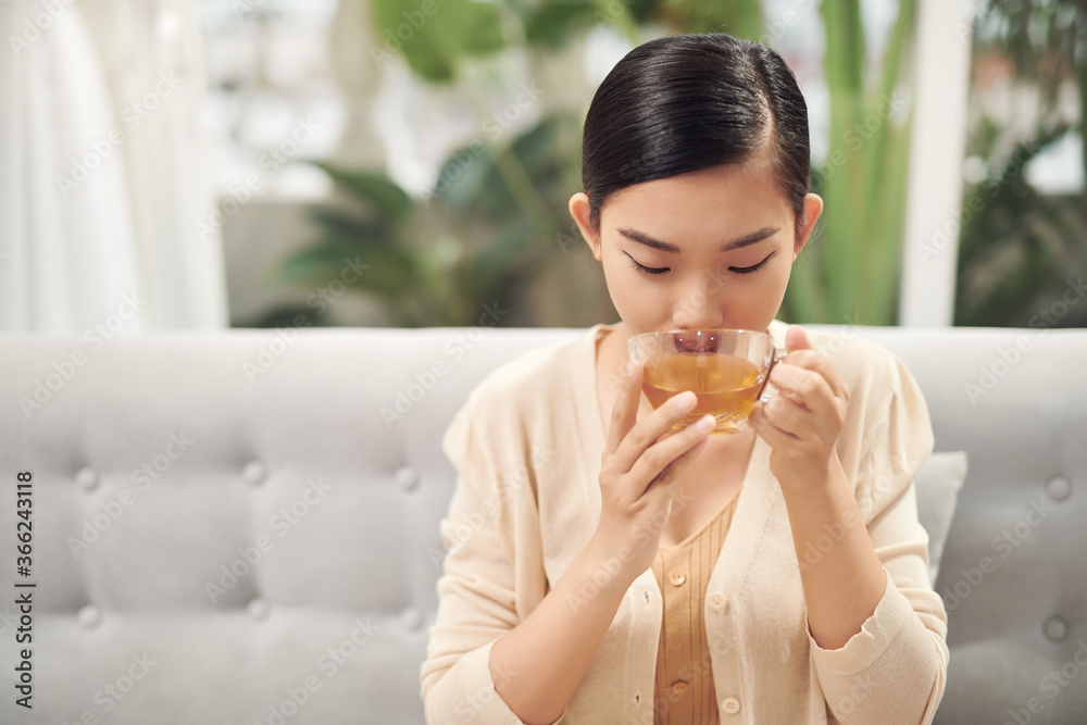 Indoor shot of a smiling asian woman drinking tea. Indoor shot of a smiling asian woman drinking tea.